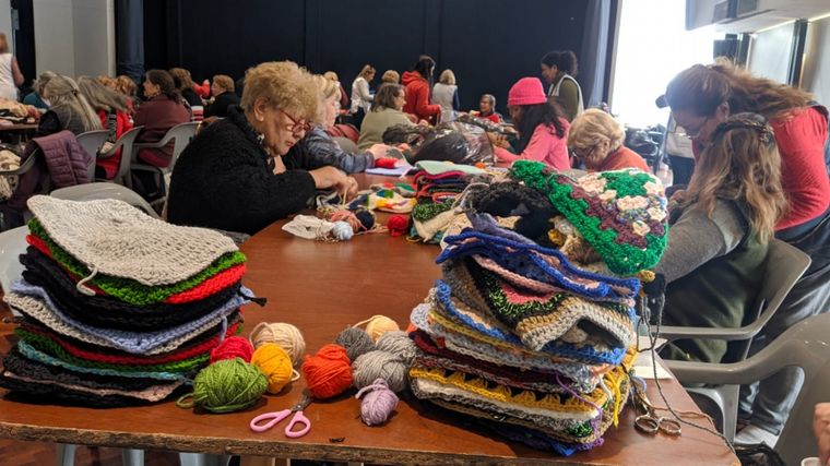 Voluntarios unen cuadraditos de lana para hacer frazadas para los más humildes.
