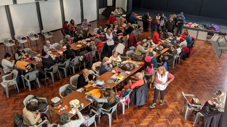 Voluntarios unen cuadraditos de lana para hacer frazadas para los más humildes.