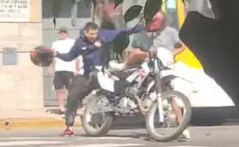 La víctima, casco en mano, intenta golpear al ladrón.