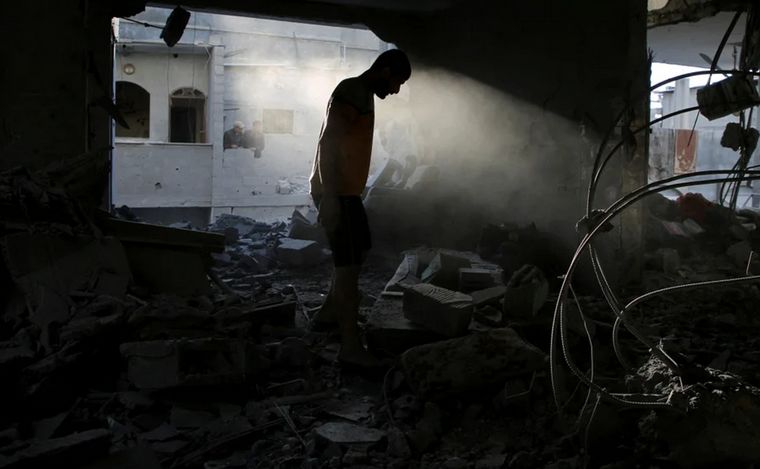 Un palestino inspeccionando una casa alcanzada por un ataque (REUTERS/Hatem Khaled).