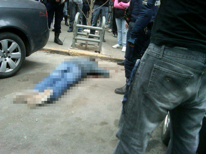 Uno de los delincuentes heridos tirado en el asfalto.