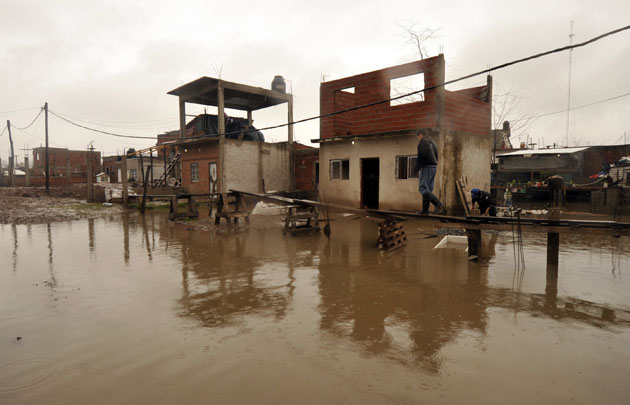 Un hombre camina sobre un improvisado andamio para acceder a su casa.