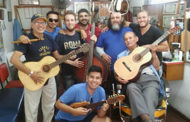 Orlando Morales junto a los jóvenes que aprenden música en la peluquería.