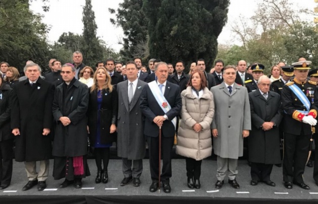 Los funcionarios presencian el izamiento de la Bandera Nacional.
