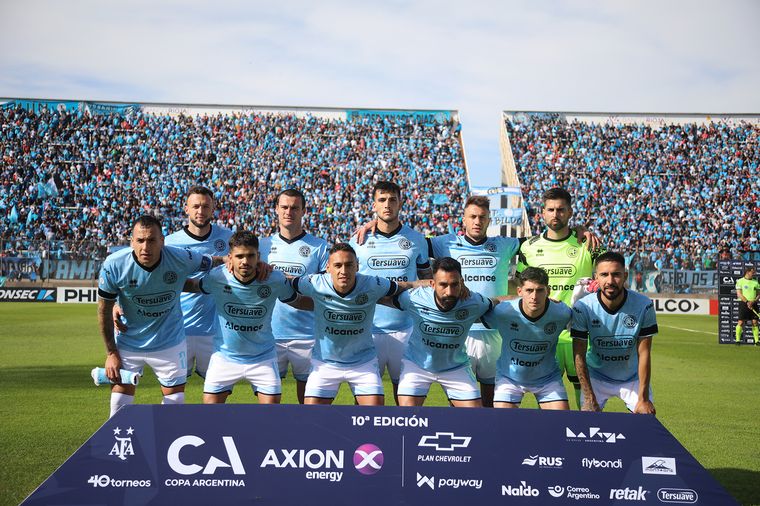 FOTO: El equipo de Belgrano, con sus hinchas de fondo.